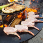 Grillen mit Würstchen und Koteletts auf offener Flamme.